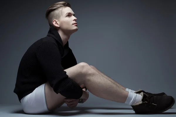 Retrato de un hombre joven de moda en ropa de moda sentado ov —  Fotos de Stock