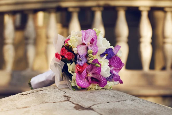 Прекрасный свадебный букет, лежащий на камне над старым домом — стоковое фото