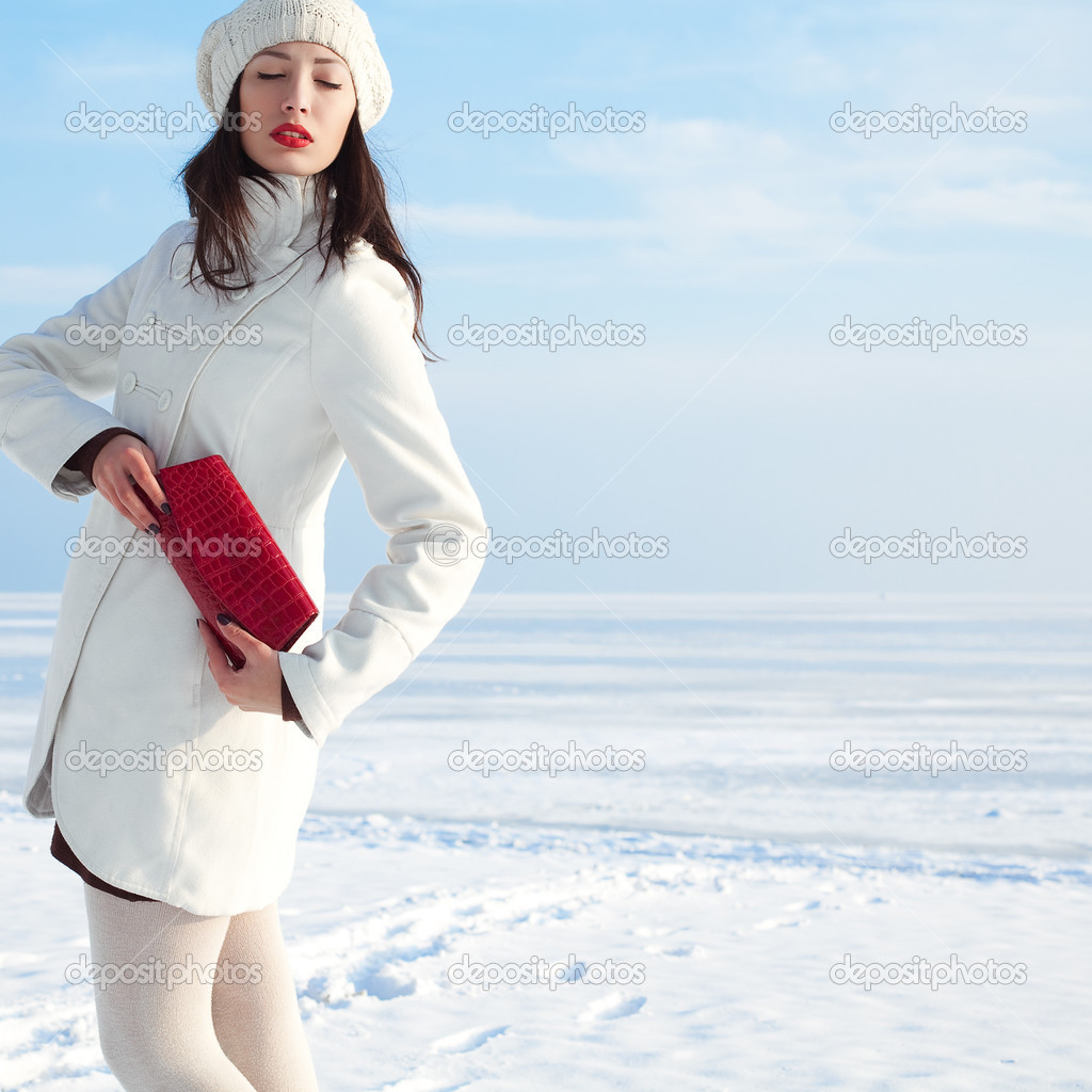 Portrait of a fashionable model in white coat and beret holding