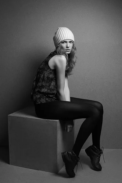 Модная модель с вьющимися светлыми волосами и белой шляпой, сидящая на — стоковое фото