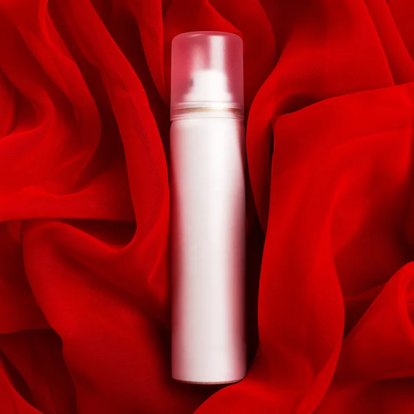 Beauty spray (aerosol) over red vapory and wavy cloth background — Stock Photo, Image