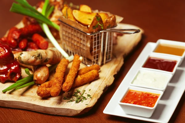 Fried cheese sticks with small meat sausages served with scallio