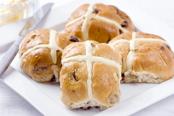 Hot Cross Buns com manteiga em uma placa branca . Fotos De Bancos De Imagens Sem Royalties