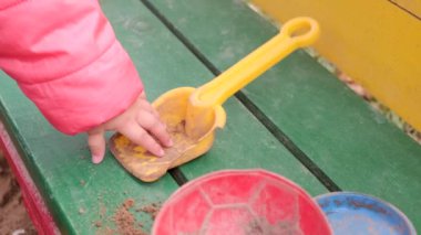 Kum havuzunda oynayan küçük kıza yakın çekim. Yavaş çekim.