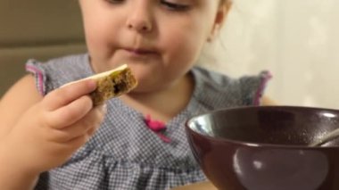 Anaokulundaki kızın bir masada oturup ekmek ve tereyağı yemesini kapatın..