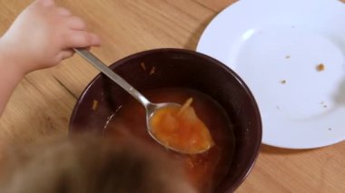 Anaokulu kızı masada oturmuş çorba içiyor. Yakın plan. Üst görünüm.