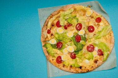 Açık mavi arka planda nefis sıcak pizzaya yakın çekim. Seçici odaklanma. Üst Manzara. Metin için boşluk.