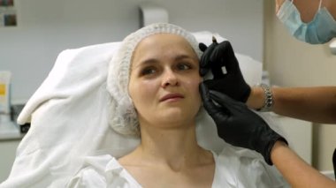 Beautician preparing woman's face for needle therapy treatment. Close-up. Slow motion.