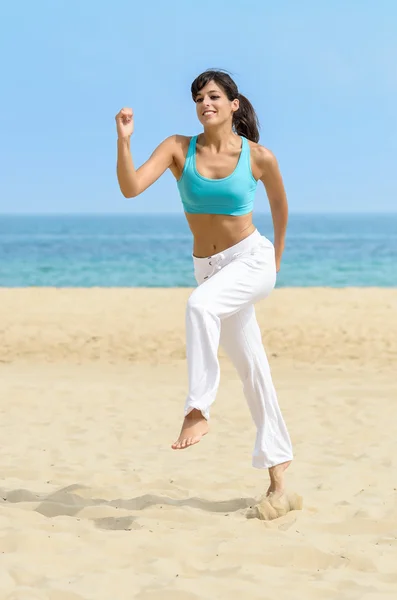 Веселая женщина бегает и прыгает по пляжу — стоковое фото