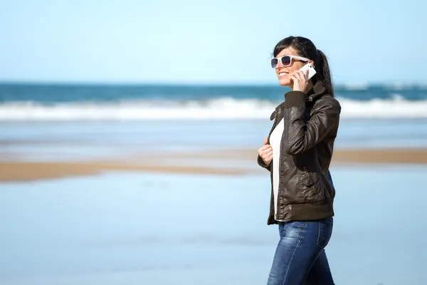 Woman with cellphone walking on beach — Stock Photo, Image