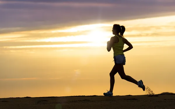 Atleta che corre al tramonto sulla spiaggia Immagini Stock Royalty Free