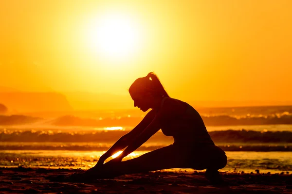 Exercícios de alongamento na praia ao pôr do sol — Fotografia de Stock