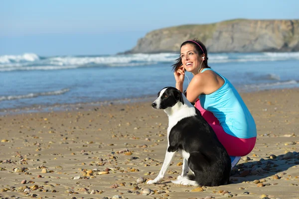 Sportieve vrouw en hond op strand — Stockfoto