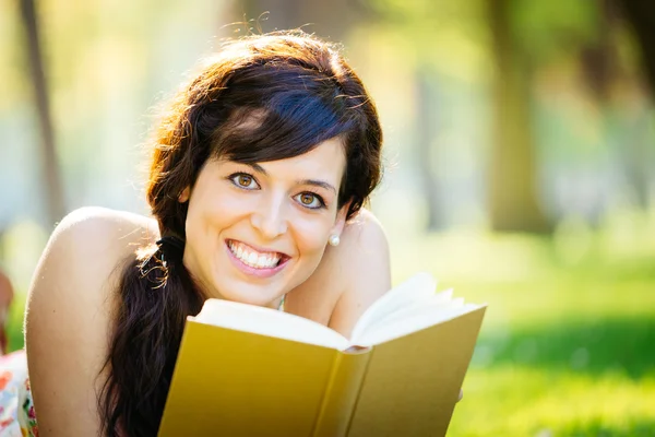 Mujer feliz leyendo libro en el parque — Foto de Stock