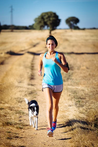 Mujer y perro corriendo por el camino rural — Foto de Stock