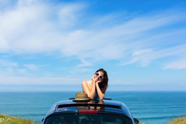 Woman on summer travel leaning out sunroof clipart