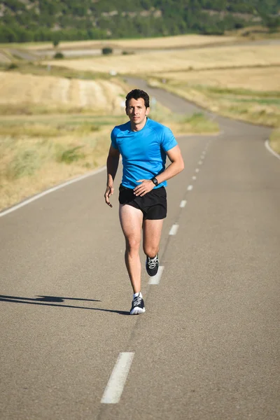 Athlete running in country road — Stock Photo, Image