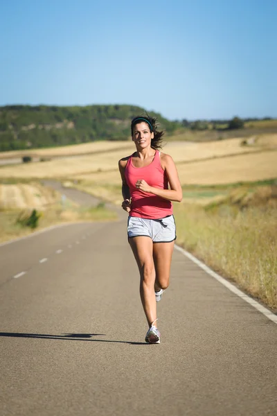 Athlète féminine en course sur route de campagne — Photo