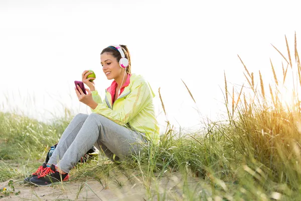 Розслаблена фітнес жінка їсть яблуко після тренування — стокове фото