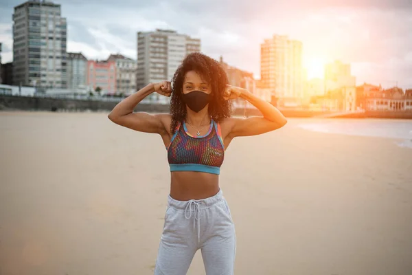 Cheerful Fit Woman Face Mask Flexing Biceps Urban Beach Fitness — Stock Fotó