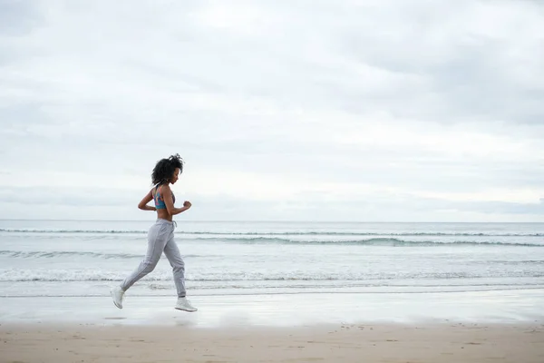 Sporty Fit Afro Hairstyle Woman Running Beach Cloudy Day — Zdjęcie stockowe