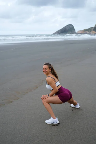 适合运动的女人在海滩上锻炼和伸展 健康的户外生活方式 女运动员的训练和锻炼 西班牙阿斯图里亚斯海岸 — 图库照片