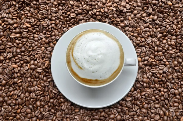 कॉफी बीन्सवर कॅप्पुचीनो — स्टॉक फोटो, इमेज
