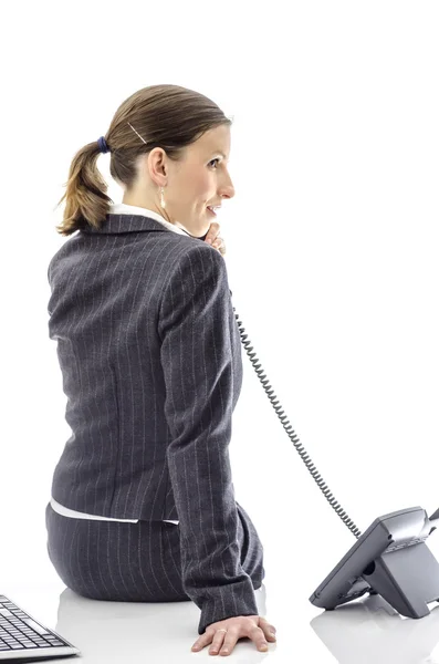 Femme d'affaires souriante assise sur un bureau blanc — Photo