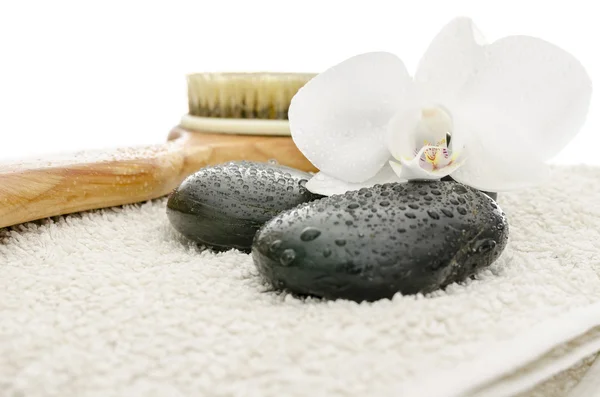 Massage stones, brush and orchid on a towel — Stock Photo, Image