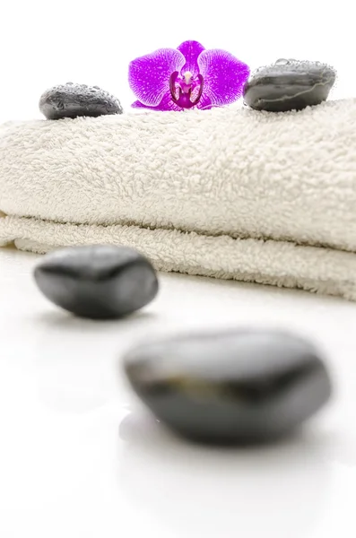 Massage stones and violet orchid flower on a towel Stock Image