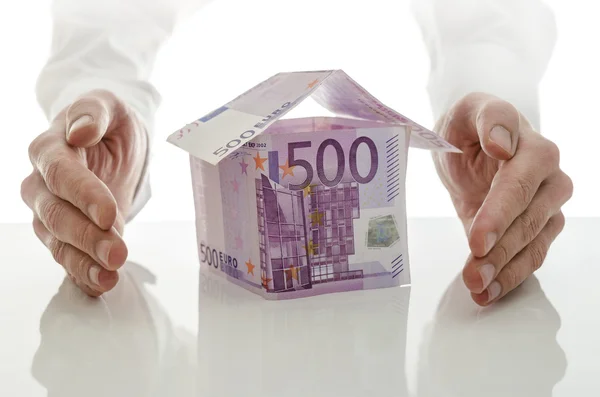 Male hands giving energy to money house — Stock Photo, Image