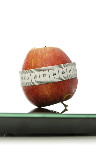 Apple wrapped with measuring tape on a scale — Stock Photo, Image