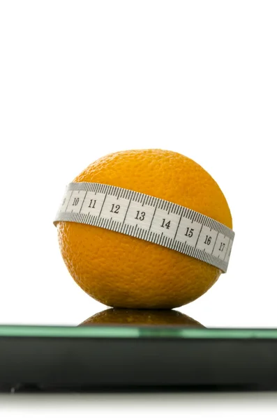 Closeup of orange on a scale wrapped with measuring tape — Stock Photo, Image