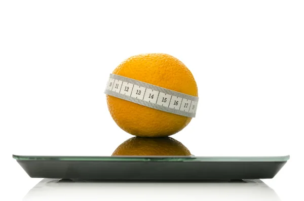 Orange wrapped with measuring tape on a scale — Stock Photo, Image