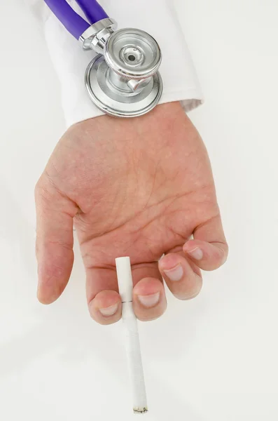 Estetoscópio em uma mão que segura um cigarro — Fotografia de Stock