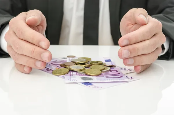 Businessman holding hands around Euro money — Stock Photo, Image