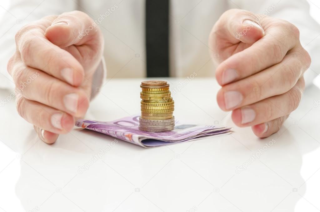 Hands around stack of Euro coins on banknotes