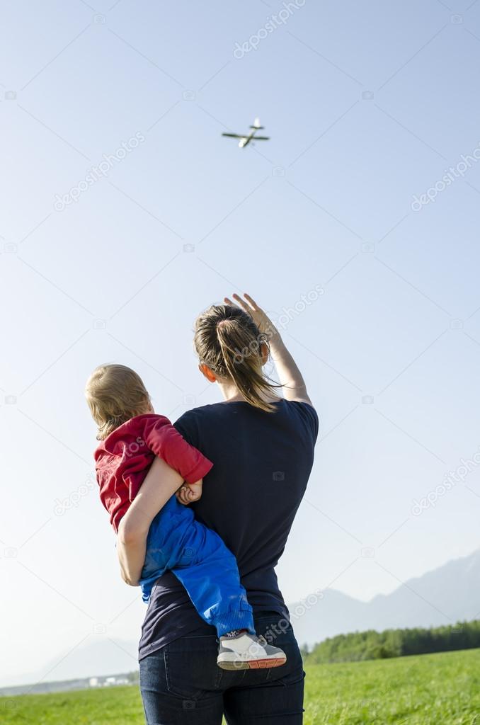 Mum and son waving at airplane