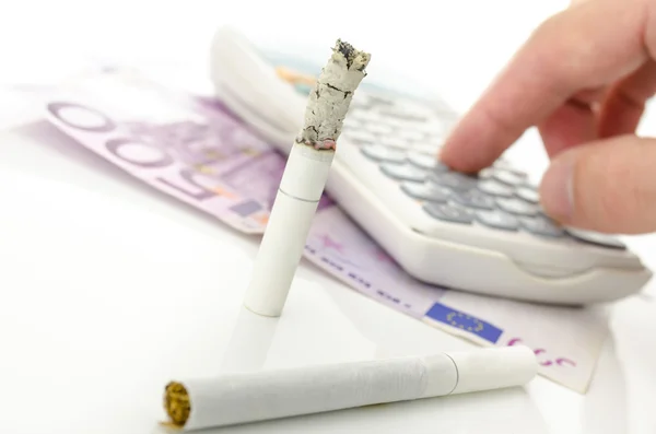 Cigarrillo medio quemado con calculadora y dinero en euros —  Fotos de Stock