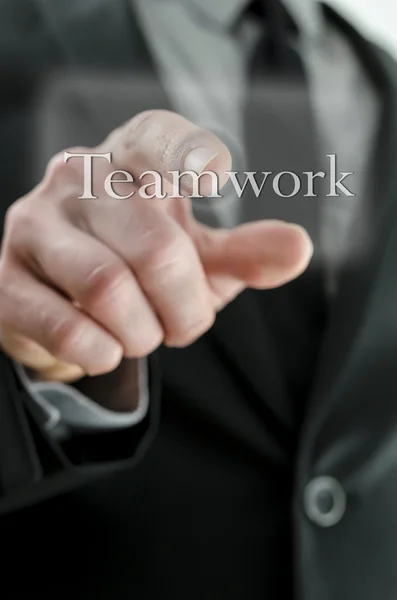 Businessman pressing Teamwork icon on a virtual screen — Stock Photo, Image