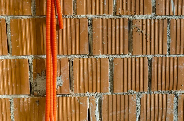 벽돌 벽에서 매달려 오렌지 플라스틱 파이프 — 스톡 사진