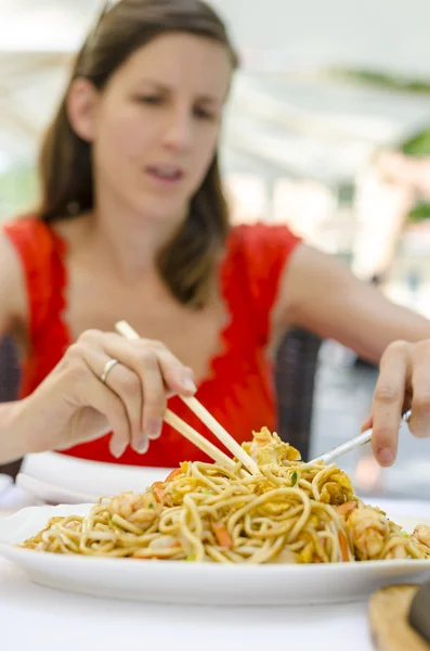 Mujer joven comiendo fideos chinos — Foto de Stock