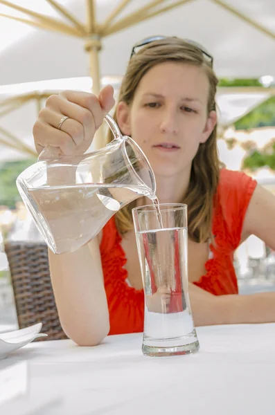 Mujer joven vertiendo agua en un vaso —  Fotos de Stock