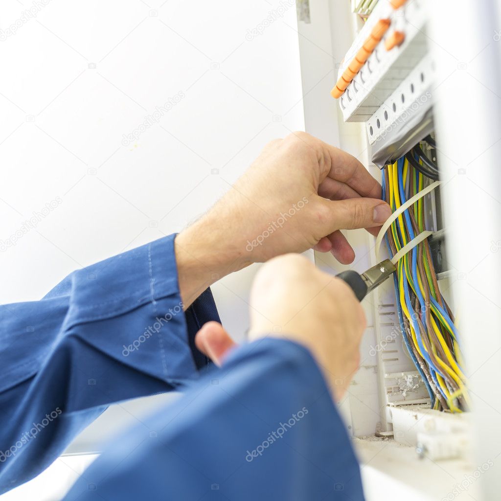 Electrician installing an electrical fuse box Stock Photo by ©Gajus