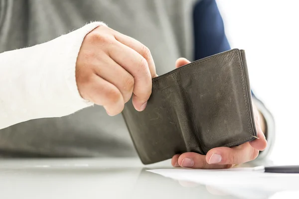 Mans arm in een gipsen houden een portemonnee — Stockfoto