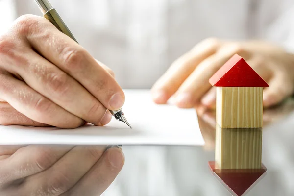 Homem que assina um contrato ao comprar uma casa nova — Fotografia de Stock