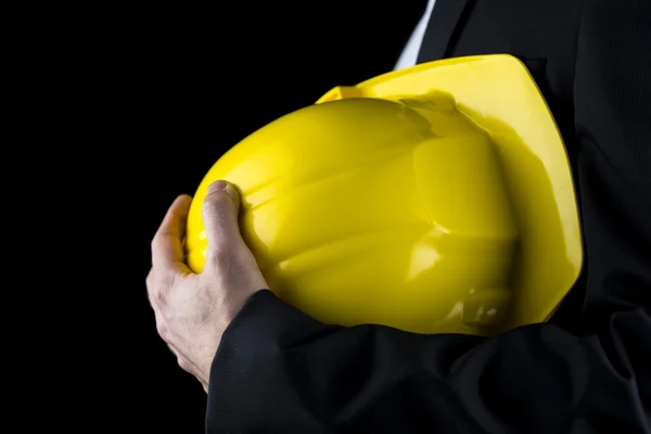 Hombre con un traje sosteniendo un sombrero amarillo — Foto de Stock