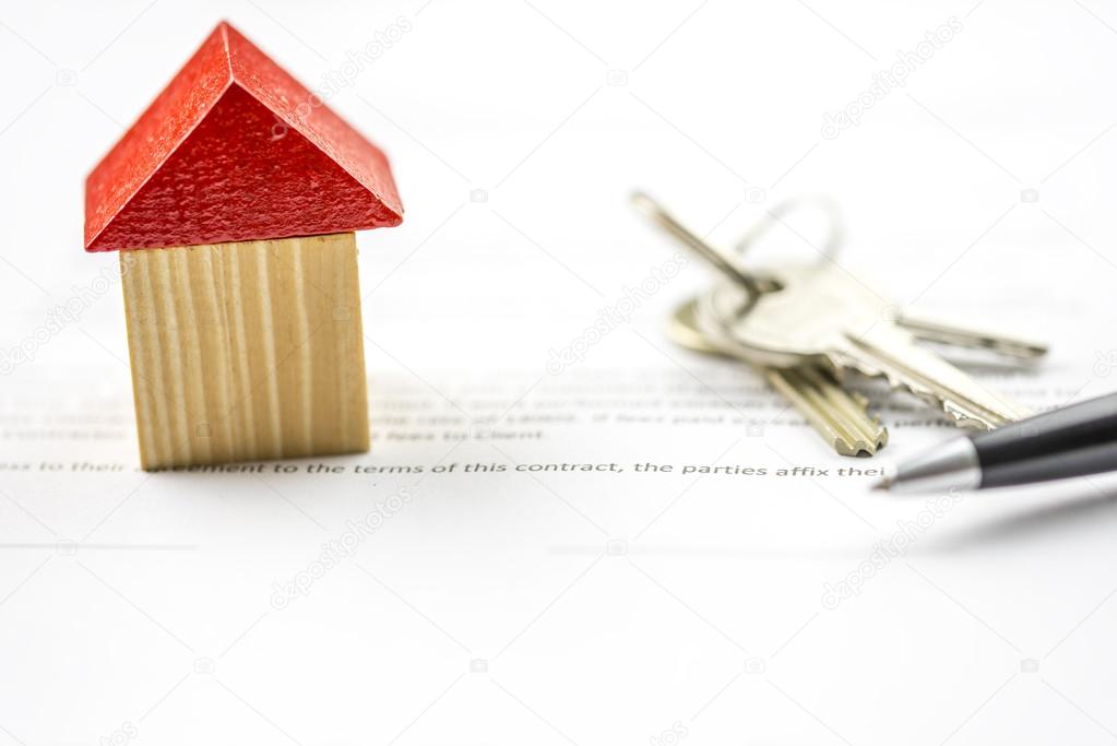 Keys and a pen alongside a model of a house