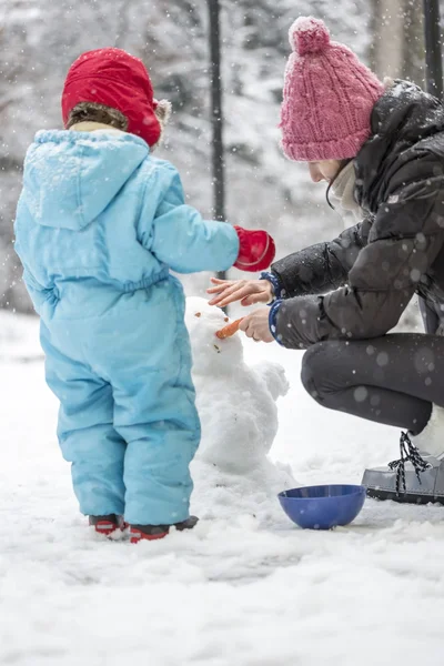Мати і дитина будують зимового сніговика — стокове фото