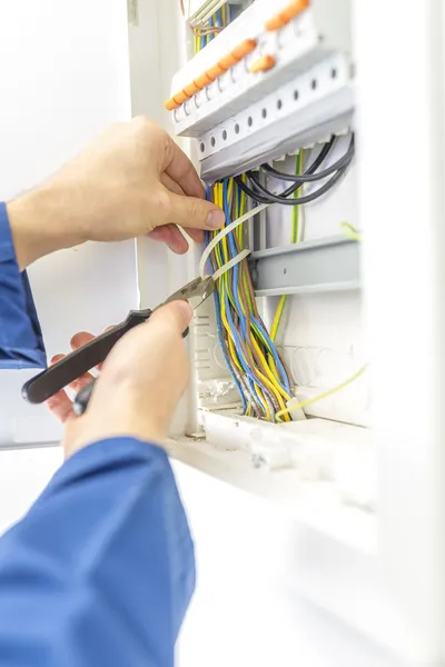 Electricista comprobando el cableado en una caja de fusibles — Foto de Stock